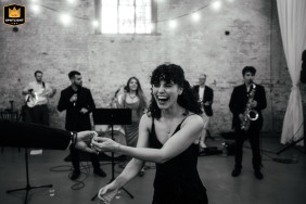 Black and white image of guests joyfully dancing at Calke Abbey, Derbyshire, with a live band in the background, capturing the lively atmosphere of the wedding celebration.